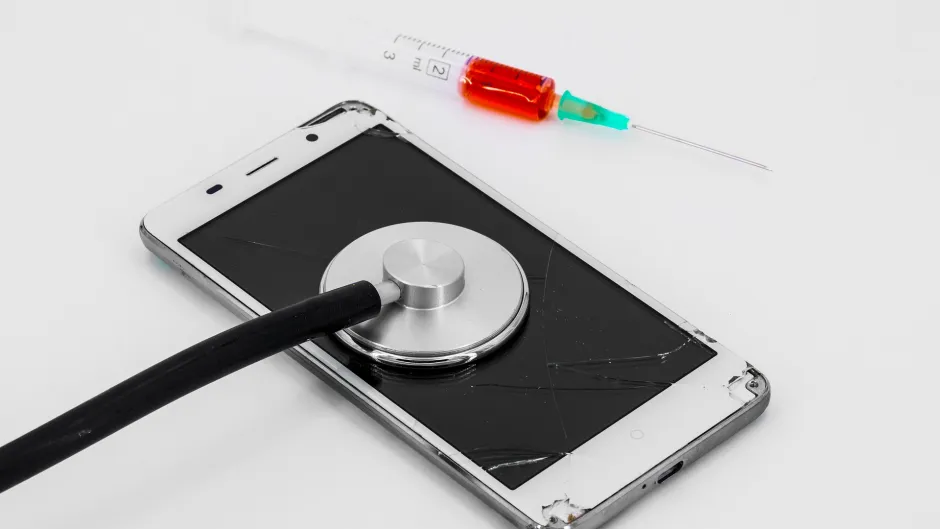 Kaputtes Handy mit Stetoskop und Spritze